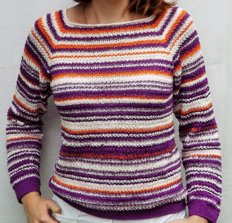 Pu&ograve; includere: Un maglione in maglia a maniche lunghe caratterizzato da un motivo a righe orizzontali nei toni del viola, arancione brillante e bianco sporco. Il capo presenta un ampio scollo rotondo e polsini e orlo a coste con lavorazione testurizzata.