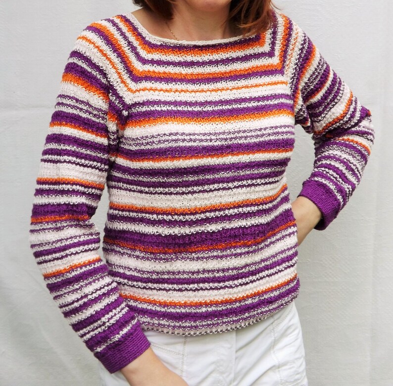 Pu&ograve; includere: Un maglione in maglia a maniche lunghe con un motivo a righe orizzontali in tonalit&agrave; vivaci di viola, arancione brillante e bianco sporco. Il capo presenta un ampio scollo a barchetta e polsini aderenti, con una lavorazione testurizzata.