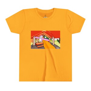 May include: Mustard yellow t-shirt featuring a cartoon graphic of a pink monkey with outstretched arms inside a red-roofed structure. The graphic includes the text "tkjo" in the lower right corner. The shirt has a crew neck and short sleeves.