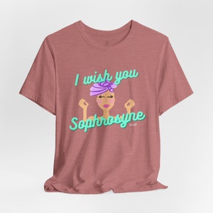 Puede incluir: Camiseta rosa polvoriento con el texto "I wish you Sophrosyne" en turquesa y una ilustración de dibujos animados de una mujer con un turbante morado. La palabra "SOUP" está debajo del nombre.