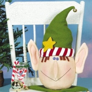 May include: A handmade felt elf head ornament with a green hat, a red and white striped band, and a yellow star. The elf has large ears, a brown nose, and a smiling mouth.