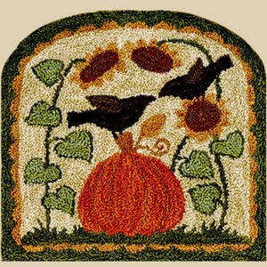 May include: A rug hooking pattern featuring a pumpkin, two birds, and sunflowers. The pumpkin is orange and the birds are black. The sunflowers are yellow with brown centers. The background is cream with green vines.