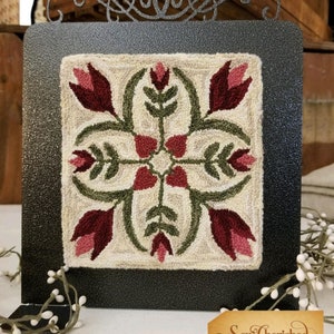 May include: A framed needlepoint rug with a floral design featuring red and green tulips on a cream background. The frame is black metal with a decorative scroll design at the top. The rug is signed "Sew Cherished".