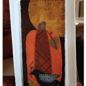 May include: A felt wall hanging with a brown, orange, and black pumpkin with a black bird perched on top. The text "Pumpkin Nights" is at the bottom of the image.
