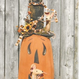 May include: A whimsical pumpkin with a painted face and a top hat decorated with fall foliage and three mice. The pumpkin is orange and the mice are beige.