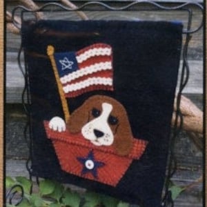 May include: A felt wall hanging with a red, white, and blue American flag and a brown and white dog in a red boat with a blue star.