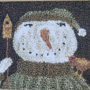 May include: A brown and white snowman wearing a green hat and holding a stick with a birdhouse on top. A small brown bird is perched on the snowman's arm.
