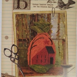 May include: A vintage-inspired craft design featuring a punched pineapple with a house design. The pineapple is orange with green leaves, and the house is red. The design measures 4 x 7.5 inches.
