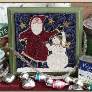 May include: A framed needlepoint design featuring Santa Claus and a snowman against a dark blue background with gold stars. The design is in a green frame.