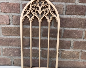 May include: A wooden cutout of a gothic arch window with intricate details. The window is made of multiple layers of wood, creating a three-dimensional effect.