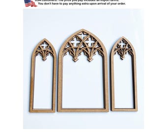 May include: Three light brown wooden window frames with pointed gothic arches. The frames feature intricate cutout tracery patterns at the top, including quatrefoil shapes. The set consists of one wider central frame and two narrower side frames.