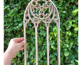 May include: A wooden cutout of a gothic arch window with intricate details. The window has four panels and a decorative top with a repeating pattern of quatrefoils.