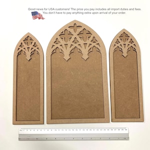 May include: Three light brown wooden panels with pointed gothic arches and intricate cutout tracery at the top. A clear plastic ruler is positioned at the bottom, showing the panels range from approximately 10 to 30 centimeters in width.