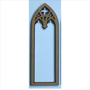 May include: A wooden, Gothic-style window frame with a decorative top. The frame is a light brown color and has a rectangular shape with an arched top. The top features a cut-out design with a cross and other geometric shapes.