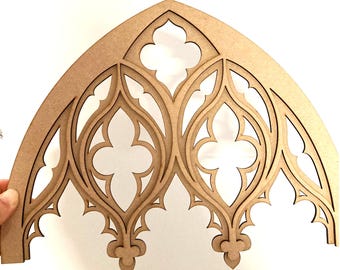 Puede incluir: Un marco de ventana de arco gótico de madera cortado con láser. El marco es de madera marrón claro y presenta intrincados diseños recortados de cuadrifolios y arcos apuntados. La forma arqueada es ideal para fines decorativos.
