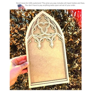May include: A light brown wooden cutout shaped like a pointed gothic arch window. The top section features intricate, layered cut-out tracery patterns with trefoil and quatrefoil shapes, while the bottom portion remains a solid, flat rectangular panel.