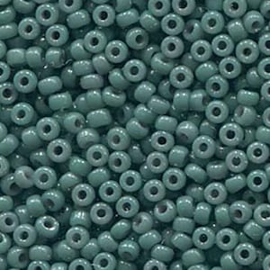 Może przedstawiać: Widok z bliska dużej ilości małych, okrągłych, turkusowych szklanych koralików. Koraliki są jednolite pod względem rozmiaru i kształtu, a ich powierzchnia jest gładka i błyszcząca.