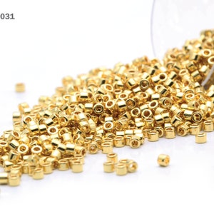 K&ouml;nnte beinhalten: Nahaufnahme eines Haufens goldfarbener Perlen. Die Perlen sind klein und rund und fallen aus einem durchsichtigen Glasbeh&auml;lter. Die Artikelnummer DB-0031 ist in der oberen linken Ecke des Bildes sichtbar.