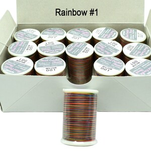 K&ouml;nnte beinhalten: Eine Schachtel mit 12 Spulen Regenbogenfarbener Perlen-H&auml;kelgarn. Jede Spule ist mit "100 Meter" und "MXZOR 001" beschriftet. Die Schachtel ist mit "Rainbow #1" beschriftet.