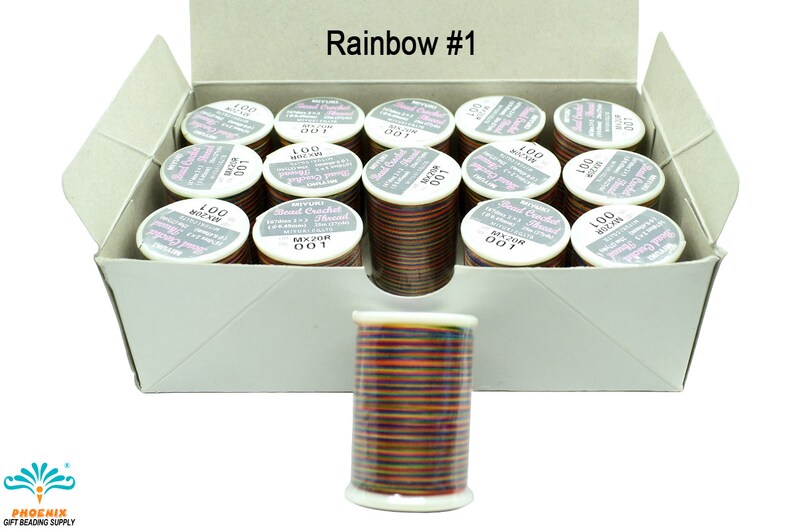 K&ouml;nnte beinhalten: Eine Schachtel mit 12 Spulen Regenbogenfarbener Perlen-H&auml;kelgarn. Jede Spule ist mit "100 Meter" und "MXZOR 001" beschriftet. Die Schachtel ist mit "Rainbow #1" beschriftet.