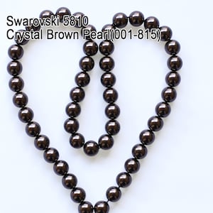 May include: A strand of Swarovski Crystal Brown Pearl beads, arranged in a heart shape. The beads are a deep, lustrous brown color, and the text "Swarovski 5810 Crystal Brown Pearl (001-815)" is visible in the image.