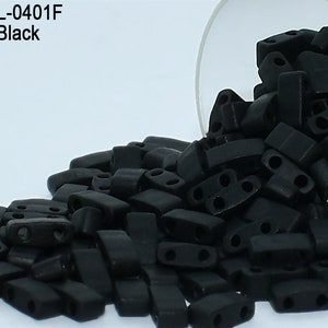 May include: A close-up of a pile of black opaque glass beads. The beads are rectangular with two holes in each. The beads are spilling out of a clear glass jar. The text "Item: HTL-0401F Opaque Black" is visible in the top left corner of the image.