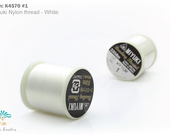 Può includere: Due rocchetti di filo di nylon bianco Miyuki per perline. Le bobine hanno etichette in bianco e nero con testo che include "Miyuki" e "Beading Thread". Il filo è lungo 50 m.