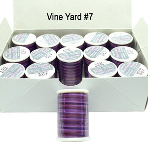 K&ouml;nnte beinhalten: Eine Schachtel mit 12 Spulen lilafarbenen Perlenfadens mit der Aufschrift "Bead Crochet Thread", der Farbnummer "007" und dem Text "Vine Yard #7".