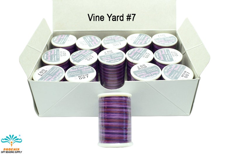 K&ouml;nnte beinhalten: Eine Schachtel mit 12 Spulen lilafarbenen Perlenfadens mit der Aufschrift "Bead Crochet Thread", der Farbnummer "007" und dem Text "Vine Yard #7".
