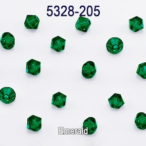 Puede incluir: Cuentas de vidrio verde esmeralda, 5328-205, dispuestas sobre un fondo blanco.