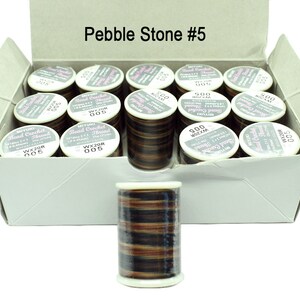 K&ouml;nnte beinhalten: Eine Schachtel mit 20 Spulen braunem, schwarzem und beigefarbenem Perlenh&auml;kelgarn. Die Schachtel ist mit "Pebble Stone #5" beschriftet.