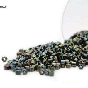 May include: A close-up of a glass jar filled with iridescent green and black seed beads. The beads are spilling out of the jar onto a white surface. The text "Item: DB-0003" is visible in the top left corner of the image.