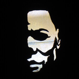 May include: A black and white silhouette of a person's face with a detailed cutout of the eyes, nose, and mouth.