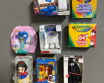 May include: A collection of small toy figurines in their packaging. The toys include a princess doll, a Star Wars character, a cartoon character, and a robot. There are also two boxes of crayons.