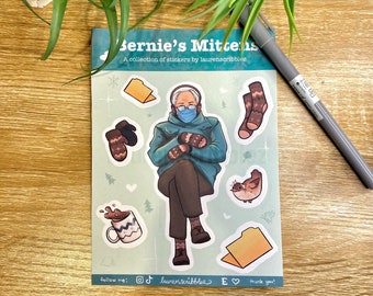 May include: A set of stickers featuring a cartoon illustration of Bernie Sanders wearing mittens and a face mask, along with other winter-themed illustrations, such as a cup of hot chocolate, a bird, and a pair of socks. The text "Bernie's Mittens" and "A collection of stickers by laurenscribblez" is printed at the top of the sheet.