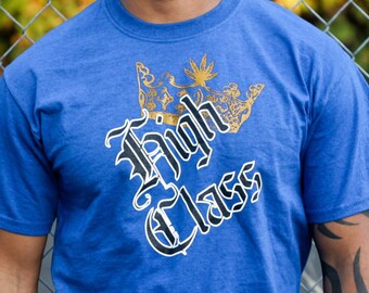 May include: A royal blue short-sleeved t-shirt featuring a gold-colored crown graphic above the text "High Class" written in a white gothic-style font with a black outline. The shirt has a crew neckline and a standard fit.