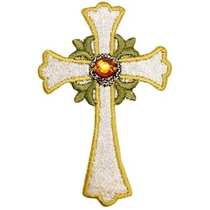 May include: A white cross with a gold outline and a green floral design. The center of the cross features a large, amber-colored jewel.