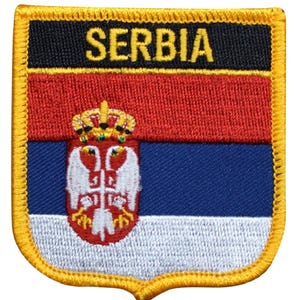Könnte beinhalten: Ein schildförmiger, bestickter Aufnäher mit der serbischen Flagge in horizontalen Streifen aus Rot, Blau und Weiß. Das Wort SERBIA ist oben in Gelb eingestickt. Ein zentrales Wappen zeigt einen Doppeladler und eine Krone.