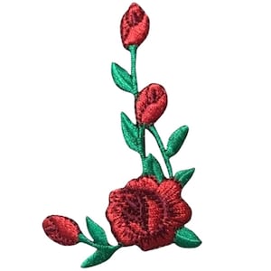 May include: An embroidered patch featuring a large red rose at the base with two smaller red rosebuds extending upward on a green stem with several green leaves. The design is stitched with red and green thread on a white background.