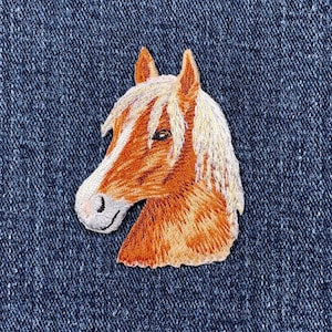 May include: An embroidered horse head patch. The horse has a tan body, a white and tan mane, and a white face. The patch is set against a blue denim background.