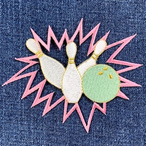 May include: Embroidered patch featuring a bowling scene. The design includes three white bowling pins with gold accents, a green bowling ball, and a pink burst effect on a blue denim background. Ideal for jackets, bags, or other fabric items.