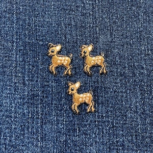 Könnte beinhalten: Drei gestickte Hirschaufnäher mit braunen und weißen Details auf blauem Denim-Hintergrund. Die Aufnäher zeigen ein Rehmotiv mit hellbraunem Körper und weißen Akzenten.