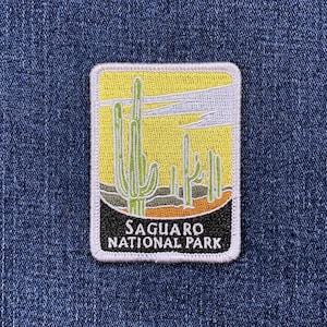 May include: Rectangular patch featuring a desert landscape with green cacti against a yellow sky. The patch has a black border at the bottom with the text "SAGUARO NATIONAL PARK" in white.