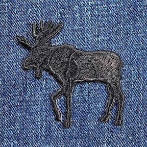 May include: Black embroidered moose patch on a blue denim background.