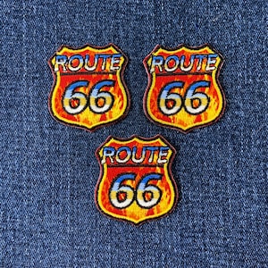 May include: Three Route 66 embroidered patches. Each patch features a shield design with the words "ROUTE 66" in blue and white, and the number "66" in white. The background has a flame design in yellow, orange, and red.