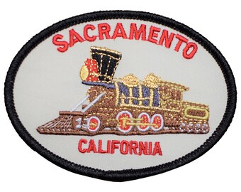 May include: An embroidered patch with a beige background and black border. The patch features a red and gold steam locomotive with the text "Sacramento, California" in red.
