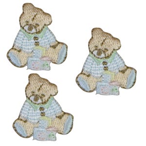 May include: Three embroidered teddy bear patches. Each bear is seated, with tan fur and a light blue sweater, holding a gift. Ideal for embellishing clothing or accessories. Each patch is suitable for sewing or ironing.