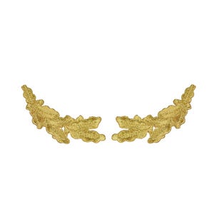 May include: A pair of gold-coloured embroidered patches shaped like curved leafy branches. Each patch features a detailed, textured stitch pattern that mimics the appearance of foliage, with a metallic sheen and a symmetrical, elongated design.