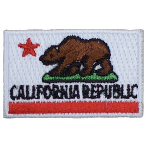 Peut inclure: Écusson brodé représentant le drapeau de l'État de Californie. Il présente un ours brun sur de l'herbe verte, une étoile rouge et les mots "CALIFORNIA REPUBLIC" en noir. L'écusson a un fond blanc avec une bande rouge en bas.