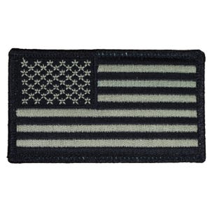 May include: A rectangular patch featuring a stylized American flag design. The flag has a black background with light gray stripes and a field of white floral-like shapes representing the stars. The edges are bordered with black stitching.